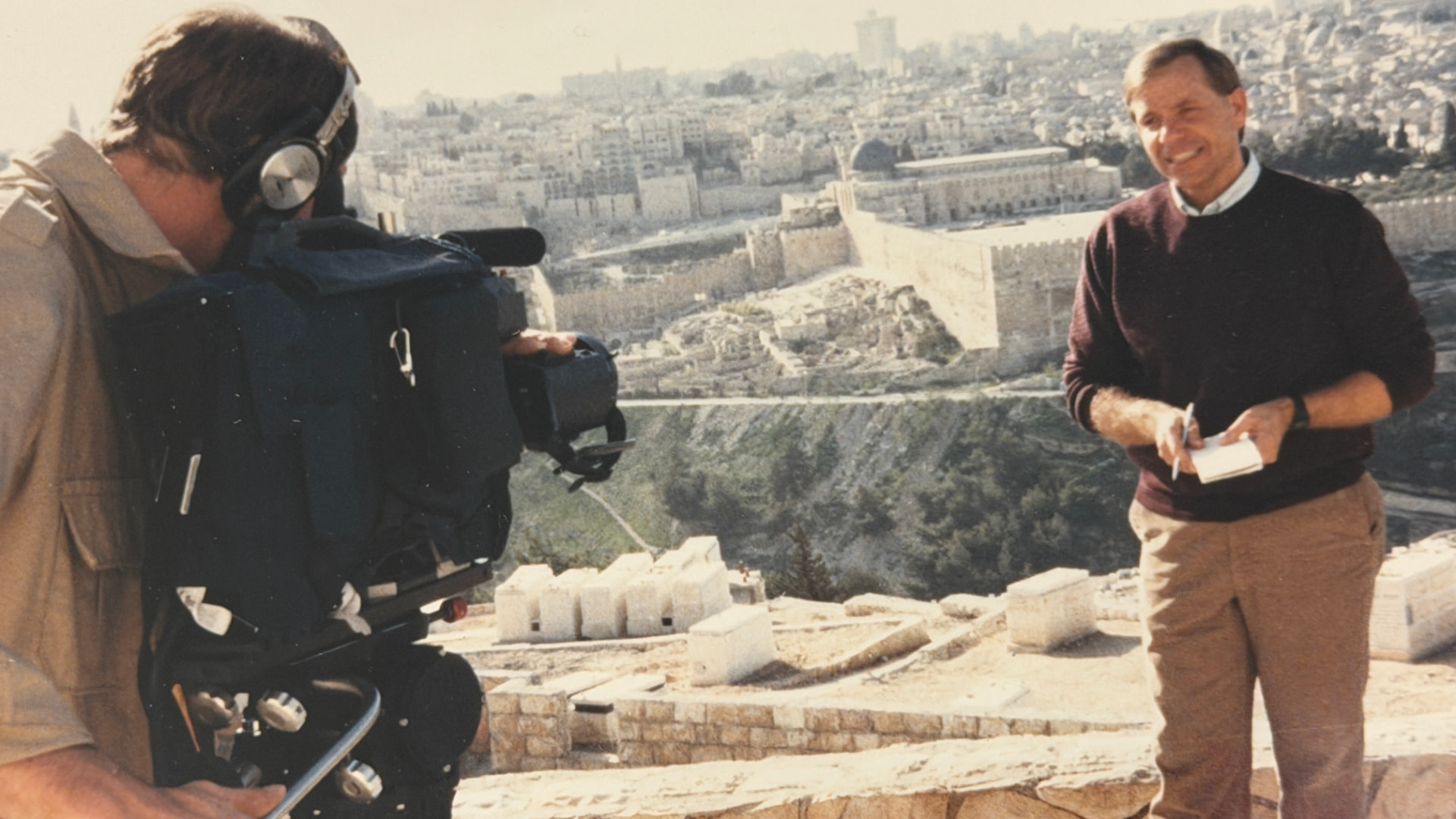 Mike Wendland on assignment in Jerusalem, reporting before a camera with the Old City behind him
